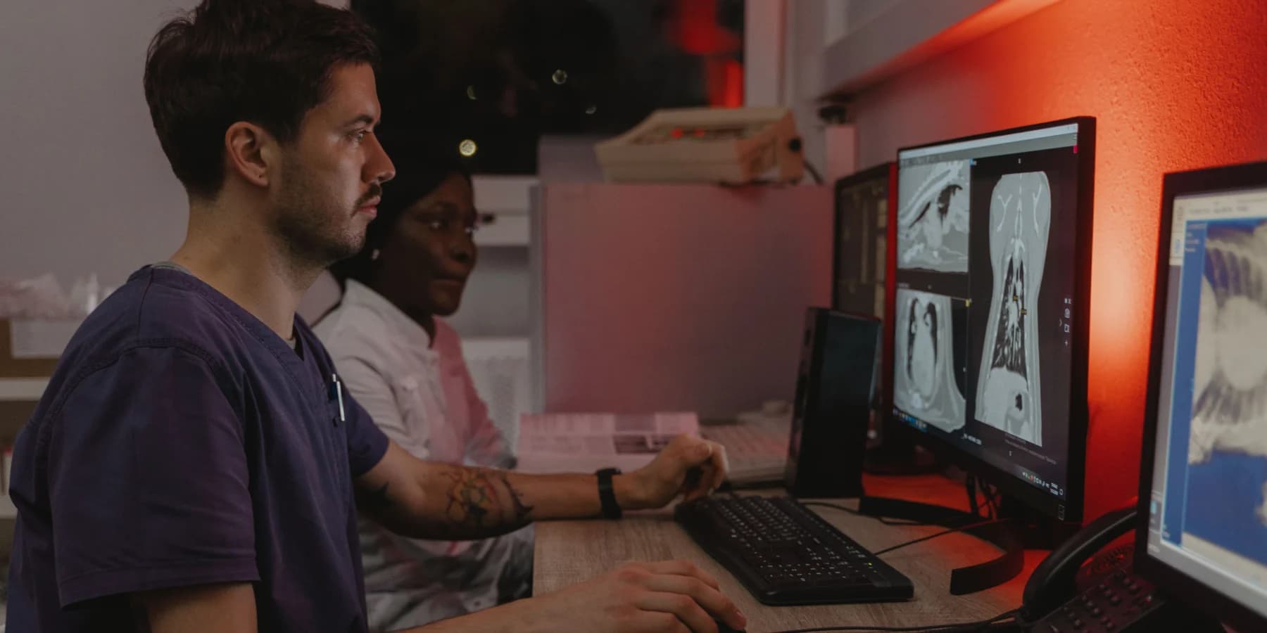 Two healthcare professionals reviewing records across multiple clinical systems
