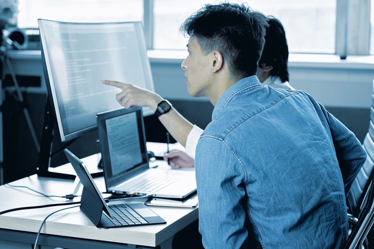 Two engineers reviewing work on a large monitor
