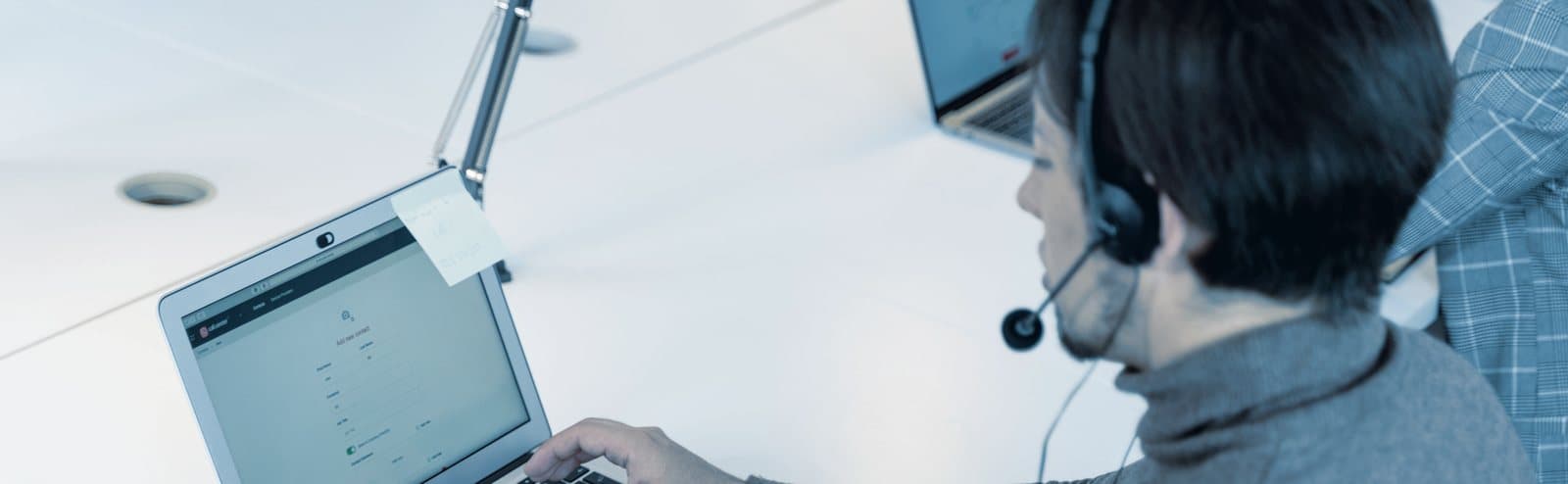 An agent working a booking on a laptop with a headset