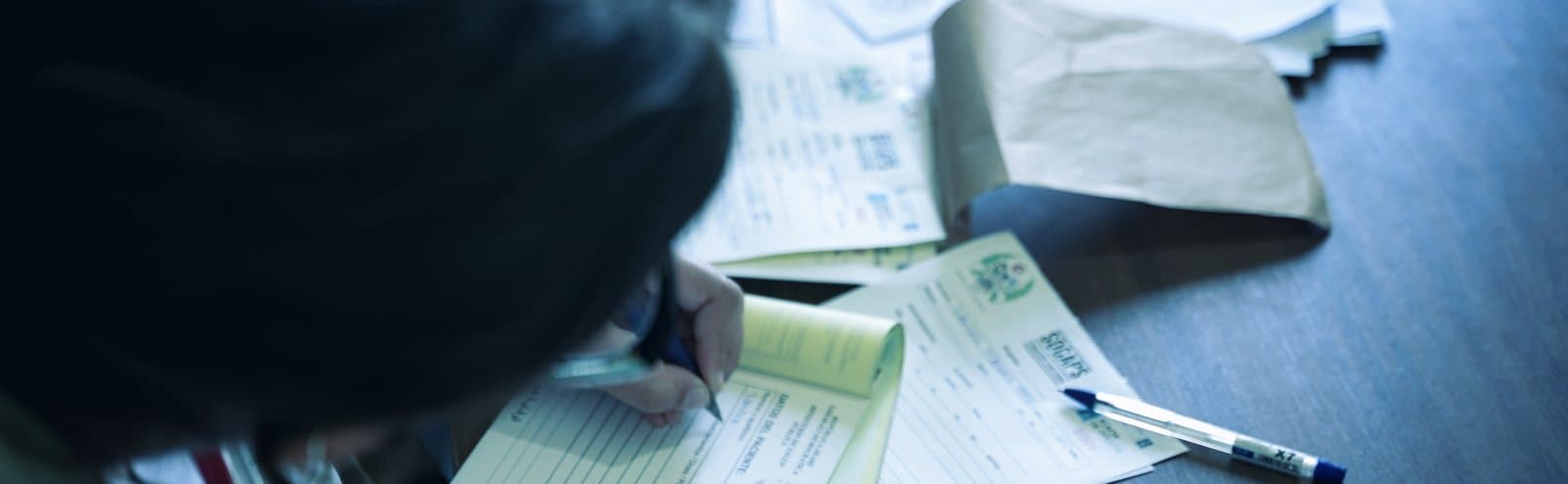 A clinician completing paperwork by hand at a desk
